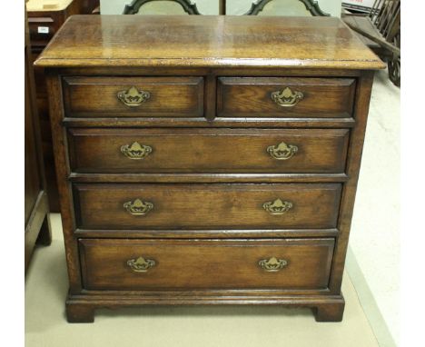 An oak chest in the 18th Century manner, the plain top with moulded edge above two short and three long drawers with brass sw