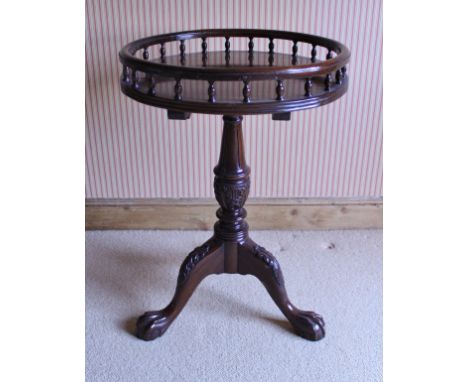 A modern mahogany occasional table in the George III taste, the circular galleried top on a carved centre pedestal to carved 
