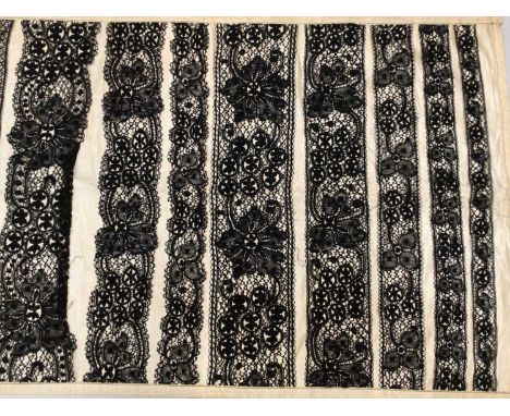 Lace items including sampler of black bobbin lace in varying width mounted on silk, deep flounce of decorated net lace with s