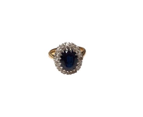 18ct gold sapphire and diamond ring with a central oval mixed cut blue sapphire surrounded by a border of diamonds (London 19