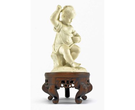 A 19th century Victorian bisque candlestick holder in the form of a seated Neoclassical cherub. The cherub seated on a tree s