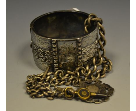 A late 19th century silver hinged bangle, engraved and chased wih leafys scrolls;   a silver Albert and fob, 110g gross