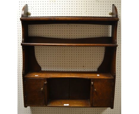 A George III oak plate rack, two shelves above pierced spoon rack, over central cavity flanked by cupboard doors