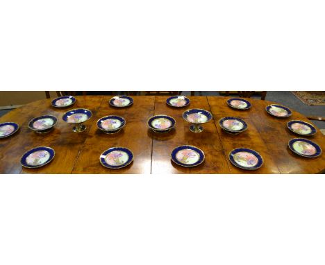 A Limoges dessert service, blue ground painted with Iris to centre, comprising four footed comports, two tall comports, twelv