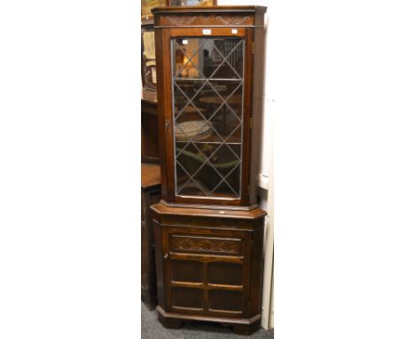 A mahogany corner display unit, oversailing top, single astral glazed glass panelled door enclosing two shelves, out stepped 