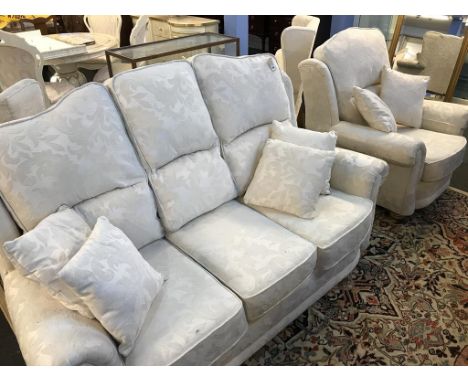 A cream three seater sofa, armchair and pair of wing chairs