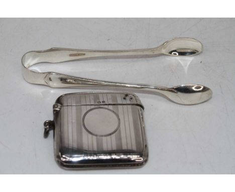 A George V silver vesta having an engine turned decoration and vacant cartouche, together with a pair of silver sugar tongs, 