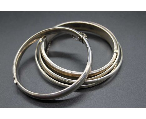 A silver and engraved hinge bangle, one other similar, together with three plain modern silver bangles (5)