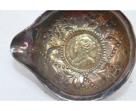 A late 18th/early 19th century white metal toddy ladle, the bowl repoussee decorated with flowers inset with a 1710 shilling 