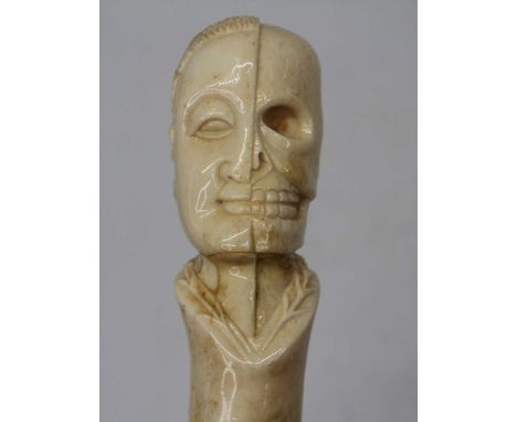 A walking stick, the bone handle carved with the bust of a gentleman half revealing his skull, 93cm