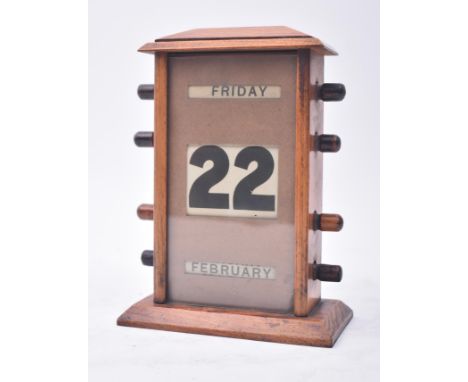 An early 20th century Art Deco oak cased English perpetual desk table calendar. The calendar having a pediment top over a gla