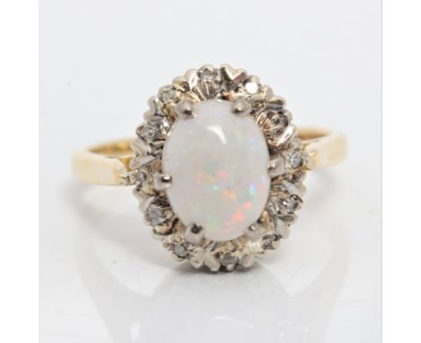 An opal and diamond cluster ring, set with an oval opal cabochon, measuring approx. 9x6mm, surrounded by a border of diamond 