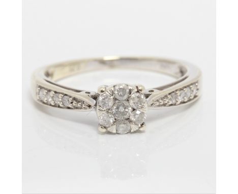 A diamond cluster ring, set with seven round brilliant cut diamonds in flower cluster, with further graduated diamond accents