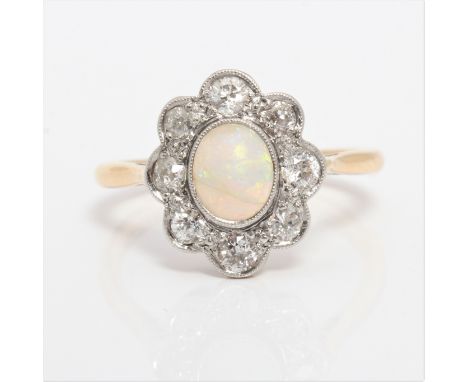 An opal and diamond cluster ring, set with an oval opal cabochon, measuring approx. 7x5mm, surrounded by a border of eight ol