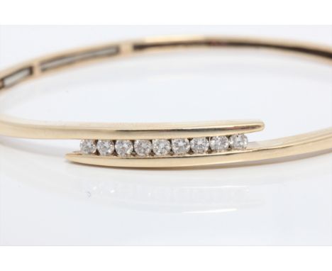 A diamond set bangle, the cross over design set with nine round brilliant cut diamonds, total diamond weight approx. 0.45ct, 