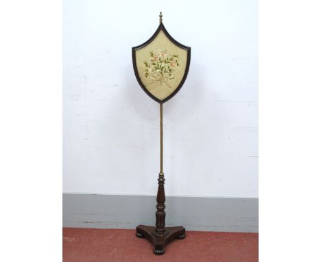A XIX Century Mahogany Fire Screen, the shield shaped floral woolwork tapestry screen on brass pole, trefoil base with gadroo
