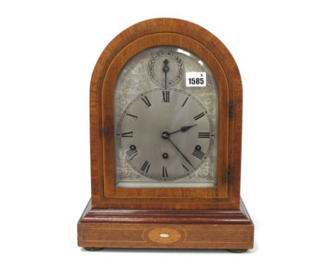 An Early XX Century Mahogany Cased Mantle Clock, the arched case inlaid in satinwood and mother of pearl, the silvered dial w