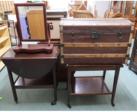 A lot comprising dome topped wood bound travel trunk, mahogany dressing mirror, and two assorted tea trolleys (4) Condition R