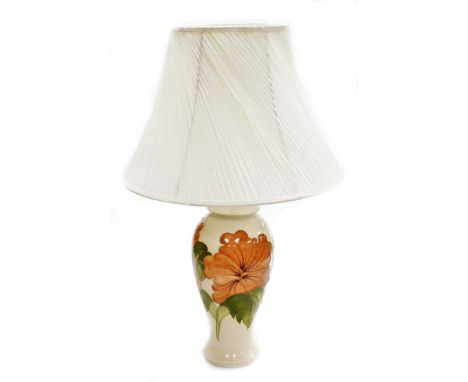 A Moorcroft table lamp, coral hibiscus pattern, in cream decoration with flowers and leaves with a cream shade, 42cm high.