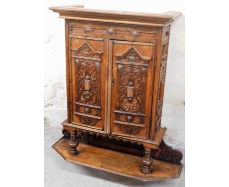 An early 20thC carved oak wall cabinet, the two doors each with scroll and harp decoration, on a pine interior with lower she