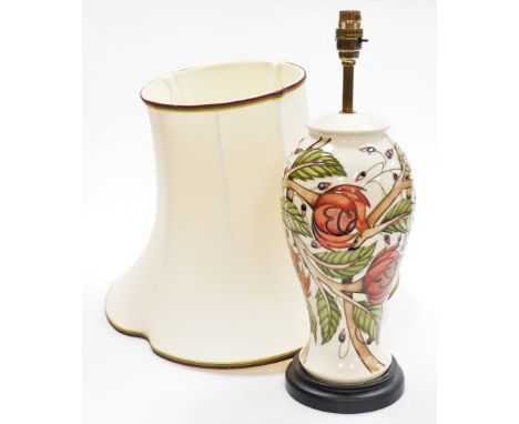 A Moorcroft table lamp, in cream decoration with berries and flowers, on mahogany base, with Moorcroft cover to underside, sh