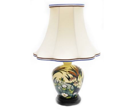 A Moorcroft table lamp, decorated with lilies, on a cream ground, on stepped mahogany base, with shade, 29cm high, boxed.