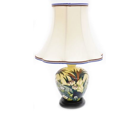 A Moorcroft table lamp, decorated with lilies, on a cream ground, on stepped mahogany base, with shade, 29cm high, boxed.