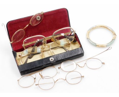 Various gilt framed spectacles and a yellow metal framed jade bangle. 