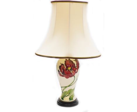 A Moorcroft table lamp, in cream decoration with red flowers and green leaves on a stepped mahogany base with Moorcroft velve