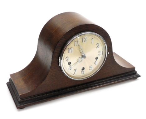 A 1950's oak cased mantel clock, with a silvered coloured dial, and an eight day striking movement, in a shaped oak Napoleon 