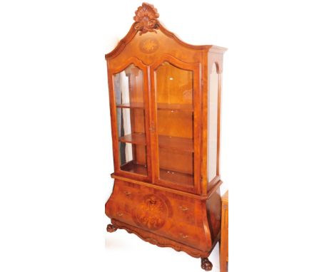 A cherry wood bombe display cabinet, the shell carved pleated top with an oval floral panel above two astragal glazed doors w