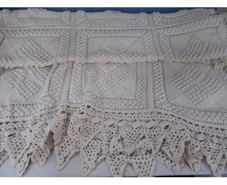 A white crocheted bed spread.