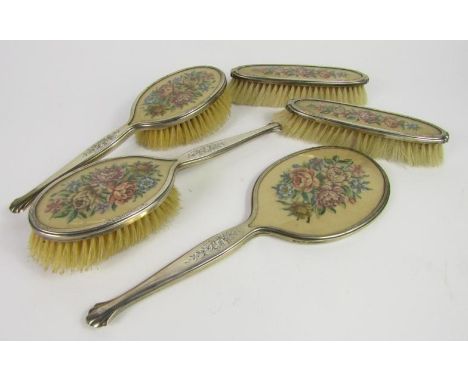 A George VI silver and embroidered floral five piece dressing table set, comprising a pair of hairbrushes, a pair of clothes 