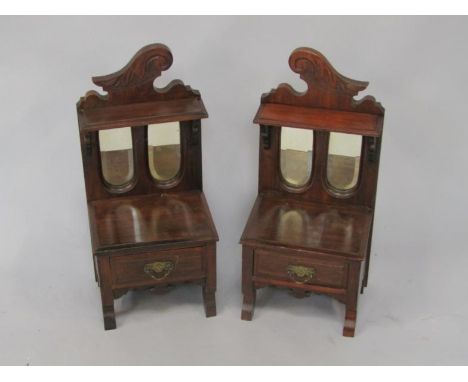 A pair of late 19thC/early 20thC side cabinets, each with two bevelled glass panels to the shelved back, above a drawer, on t