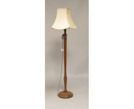 An early 20thC mahogany standard lamp , with curved leaf and fluted decoration, raised on a circular base, extending shade 15