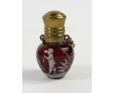 A Mary Gregory type red glass miniature scent bottle, decorated in white enamel with a boy amongst trees, hinged brass lid an