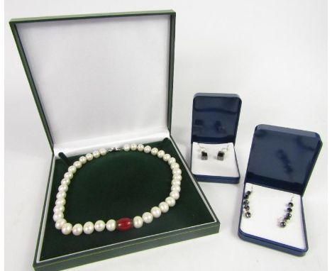 A cultured pearl necklace, on a white gold plated clasp, and two pairs of Enhanced Black Diamond earrings, boxed with certifi