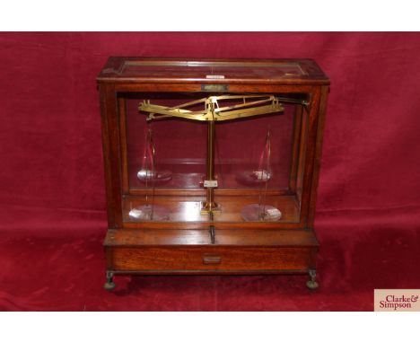 A set of brass chemist scales by L Gertling of London, in glazed wooden case and set on wooden box base with drawer and brass