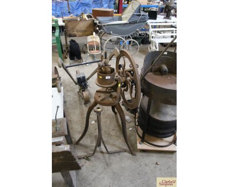 A cast iron hand operated bone crusher and an iron stool base