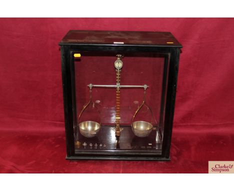 A set of chemists brass and stainless steel chemists scales with inset scoop trays and some weights, set in ebonised glazed c