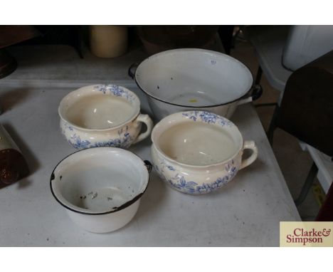 An enamel twin handled washbowl, an enamel chamber pot and two blue and white floral decorated china chamber pots 
