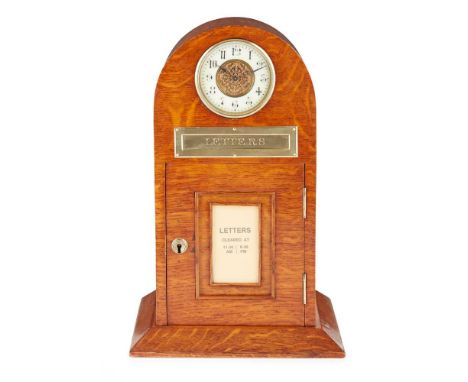 EDWARDIAN OAK AND BRASS LETTER BOX AND CLOCK EARLY 20TH CENTURY the arched top set with a clock with a cream enamel dial with