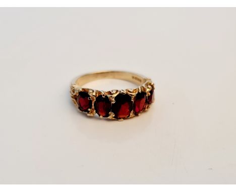A hallmarked 9ct yellow gold boat shaped ring of five graduated garnets with patterned shoulders, ring size O, approx. weight