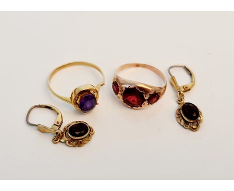 A yellow metal ring of three graduated red stones, ring size K, and a yellow metal gem stone ring, ring size P, (both rings A