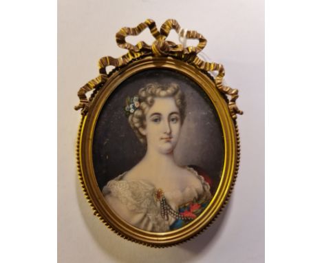 A 19th century portrait miniature on ivory of a lady with flowers in her hair and white dress with pearls in ornate gilt meta