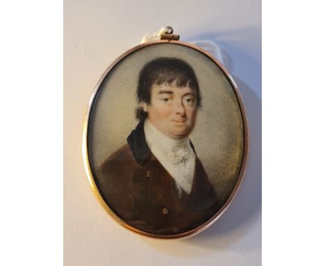 An early 19th century portrait miniature on ivory of a Georgian gentleman in brown coat in gold coloured metal frame with hai