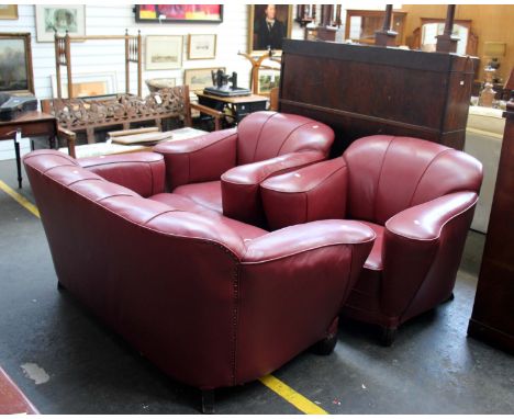 An Art Deco three piece leather suite in red (recently re upholstered). Two seat sofa and two tub arm chairs on carved mahoga