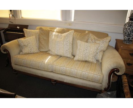 A cream upholstered three piece suite by Wade. To include a two seater sofa with two armchairs on wooden bases with show wood