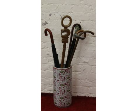 A decorative ceramic stick stand and contents of walking sticks and umbrella.