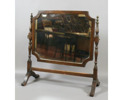 An oak framed cheval mirror raised on turned supports.